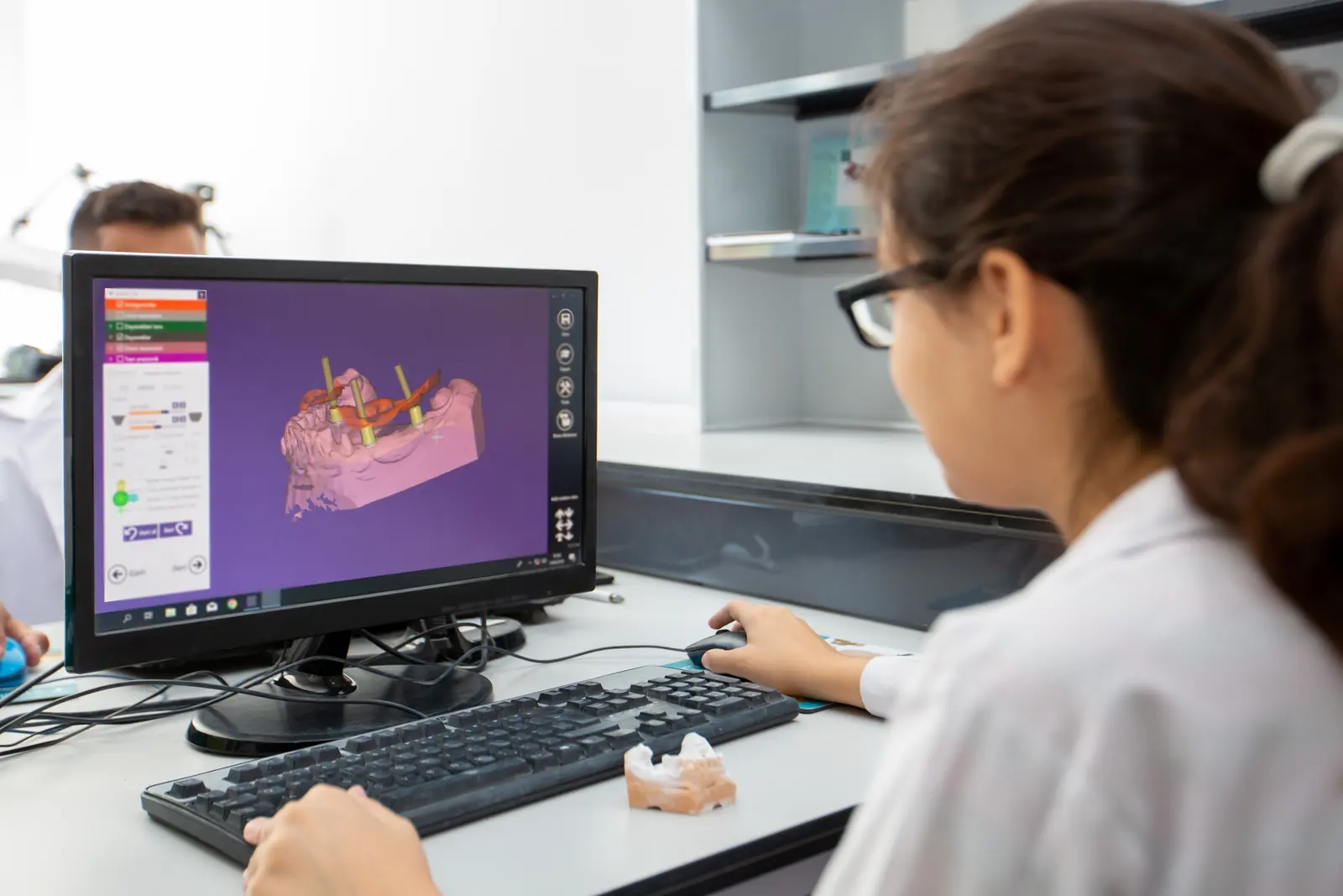 Tehnician dentar proiectând o lucrare protetică într-un program CAD